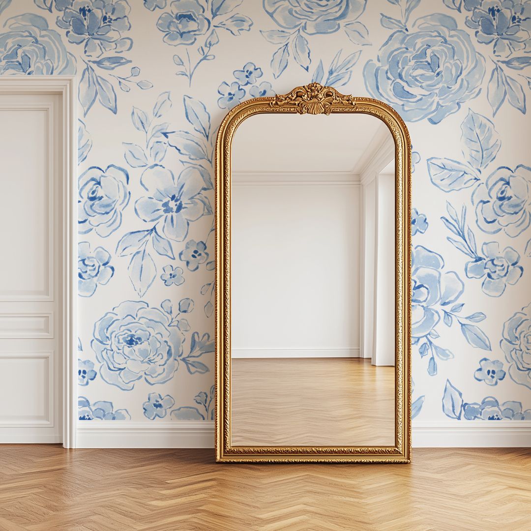 A mockup image featuring a watercolor blue coquette floral wallpaper and a large gold mirror.