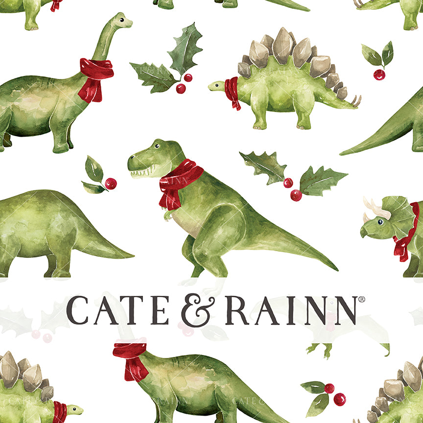 Pattern of green dinosaurs with red scarves and holly leaves on a white background, featuring the brand 'Cate &amp; Rainn'.